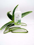 Bote de gel de baño natural con aloe vera con unas hojas de aloe vera de fondo