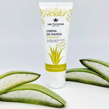 Bote de crema de manos de Aloe Vera Las Coronas acompañada por dos hojas abiertas de Aloe Vera